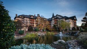 exterior of Christmas Inn with pond with sprouting fountain in foreground surrounded by plants during day with blue sky in Pigeon Forge, Tennesee, USA